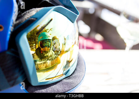 Reflections of woman and children and beautiful mountains on a ski goggles, glass of wine, coffee and cake Stock Photo