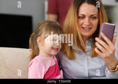 Mother and her baby girl daughter using cellphone for calling siblings Stock Photo