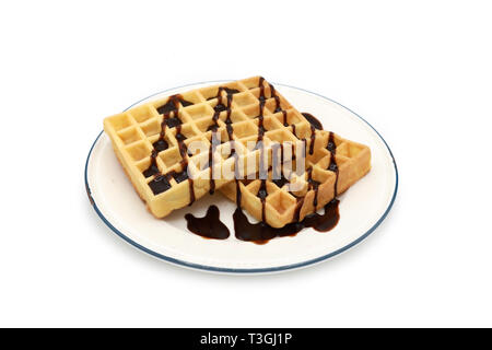 fresh belgian waffles topped with chocolate sauce on a plate isolated on white background Stock Photo