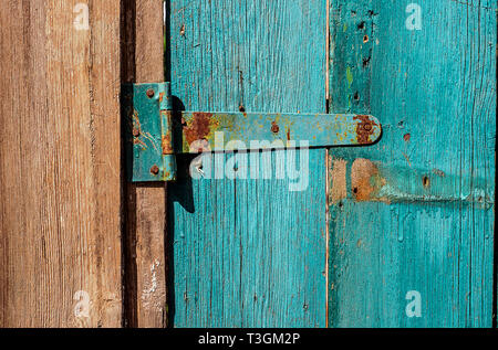 Rusty Door hinge on blue painted wood door with cracked and scratch. Horizontal grunge texture. Stock Photo