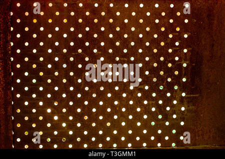 Texture of Perforated rusty iron sheet befor light. Surface of industrial mesh. Stock Photo