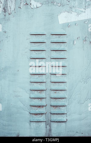 Two rows of perforated air vents on steel door in switchboard. Texture with paint stains and rusty. Stock Photo