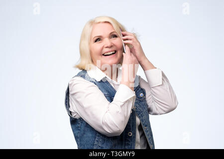 Smiling senior blonde woman talking on phone Stock Photo