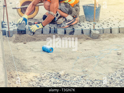 Worker lays granite tiles on the pavement Stock Photo