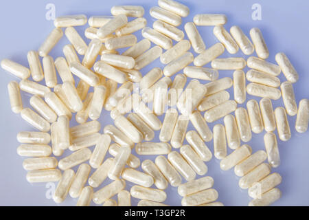 Lots of colorful drugs and pills on blue mirror background. Scattered multi-colored capsules. Health care concept. Stock Photo