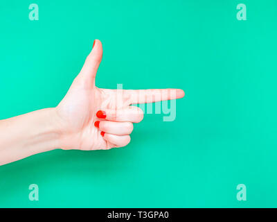 The Finger Gun Hand Sign. Is used as a way to say Yup with your hands. Pointing index finger on isolated turquoise green color background Stock Photo