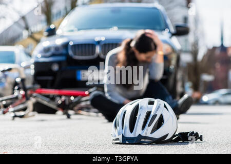 Helmet on the asphalt after accidental collision between bicycle and car Stock Photo