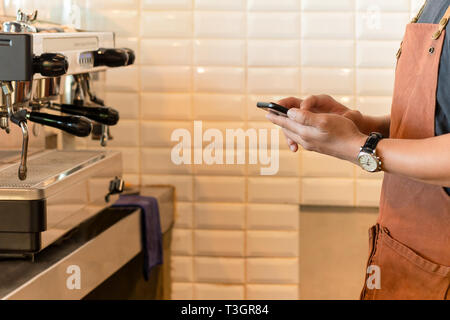 Barista checking cell phone in coffee shop. Stock Photo