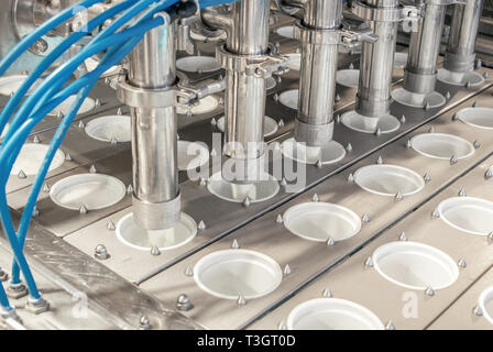 unit for pouring yoghurt into plastic jars at a dairy factory Stock Photo