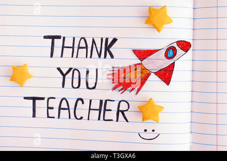 Thank You Teacher. Lined paper notepad with words Thank You Teacher and with Space Rocket Blasting Off  Through Yellow Origami Stars. Close up. Stock Photo