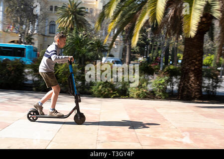 Boy riding scooter on pavement in central Malaga, Spain Stock Photo