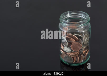 Glass jar containing UK coins - as metaphor for personal savings, rainy day saving, pensions savings pot, saving pot.