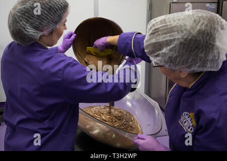 Chocolatiers pour tempered chocolate as they create a giant chocolate egg at Cadbury World in Birmingham to celebrate Easter. Stock Photo
