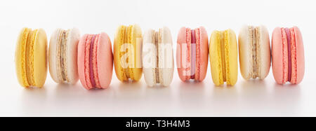 Pink, yellow and white macarons in a row on white background. Banner. Stock Photo