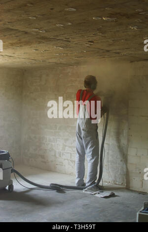 young man grinds wall in basement cellar for renovate Stock Photo