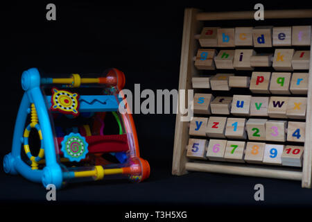 Two similar childrens toys. One plastic and one wood against a black background Stock Photo