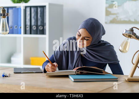 Female Muslim student reading book Stock Photo
