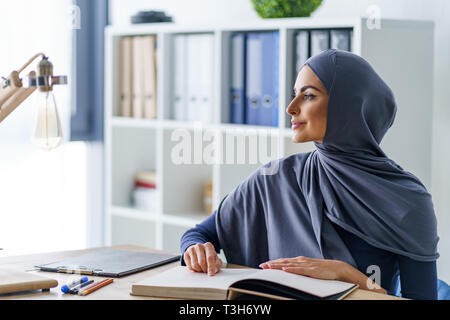 Pensive woman distracted while reading Stock Photo