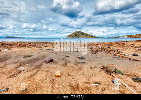 Beach sea sand stones and an island on a stormy and cloudy winter day Stock Photo