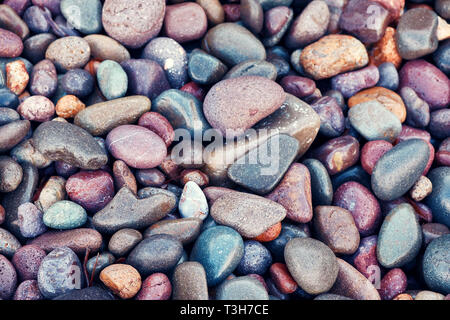 Top down closeup view of beautiful pastel colored wet pebbles at the seaside. Stock Photo