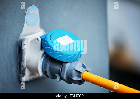 Charging station power supply for boats at the marina jetty. Electrical power socket is connected to the charger, close up view. Stock Photo