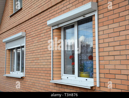 Rolling shutters house windows protection. Brick house with metal roller shutters on the windows Stock Photo