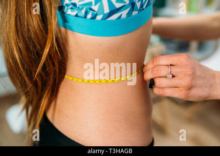 Doctor taking patient's body fat measurements on waist and abdomen with fat caliper Stock Photo