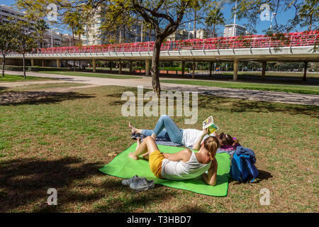 Rest in Turia gardens nearby Flower Bridge Valencia Puente de Las Flores Valencia City Spain Europe two women relaxing on blanket reading book outside Stock Photo