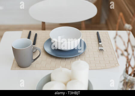 Top view of various dishware on the white dinner table - ceramic plates, cup, fork, spoon and knive Stock Photo