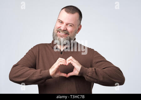Mature man with beard making out of the hands heart. Stock Photo