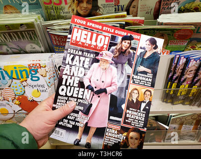 MONTREAL, CANADA - MARCH 28, 2019: Hello magazine in a hand with Queen Elizabeth on front cover over stand of different magazines in a store. Hello is Stock Photo