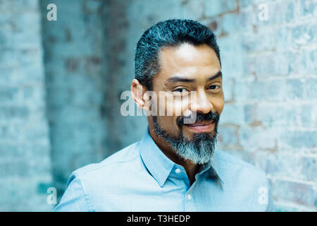 Portrait of a friendly, smiling man with silver beard in grey shirt Stock Photo