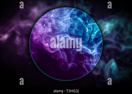 Close-up dense multicolored smoke of   blue and purple colors    blown under a magnifying glass on a black isolated background. Background of smoke va Stock Photo