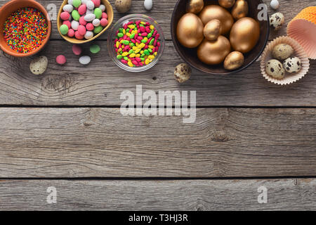 Golden eggs and candies on wooden background Stock Photo