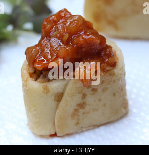 Chicken wrap appetizers covered with tomato, roasted pepper and herbs Stock Photo