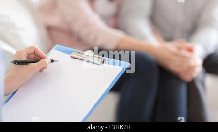 Psychotherapist writing in blank notepad at therapy session Stock Photo
