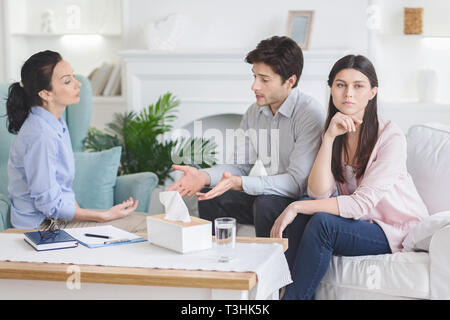 Upset man talking to psychiatrist during couple counseling session Stock Photo
