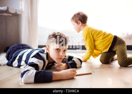 Two happy children playing at home, drawing. Stock Photo