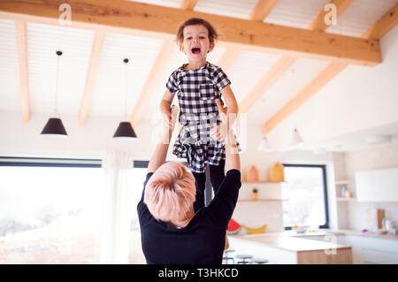 A rear view of young woman with small daughter playing at home. Stock Photo