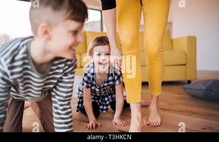 A midsection of young woman with two children playing at home. Stock Photo