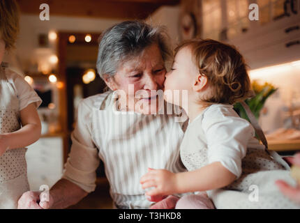 Senior grandmother with small toddler children making cakes at home. Stock Photo