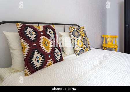 colorful pillows on the bed in Interior of the modern bedroom in loft flat apartments in light color style Stock Photo