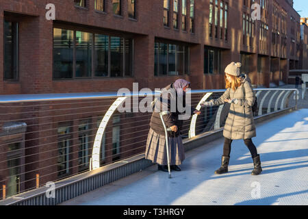 LONDON, UK – Dec 13, 2018: Old beggar receiving money from a kind young woman Stock Photo