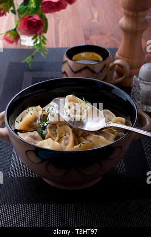 Boiled homemade dumplings with greens and sour cream Stock Photo