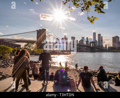 Tourists and local alike relaxing on a lazy sunny day while gazing brooklyn bridge and new york city skyline Stock Photo