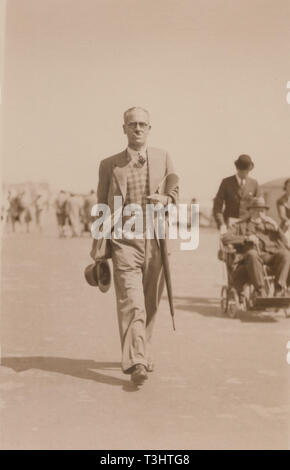 Vintage Hove, Sussex Photographic Postcard Showing a Fashionable Gentleman Walking Along a Seaside Promenade, Smoking and Carrying His Hat and Umbrella. Stock Photo