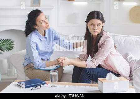 Psychologist comforting sad female patient in office Stock Photo