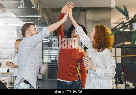 Happy coworkers having fun, giving high five during coffee break Stock Photo