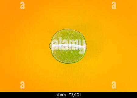 Pop art style green lemon slice on vibrant yellow color background. Minimal flat lay food texture with plenty of free space for inserts around the Stock Photo