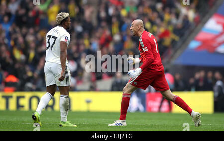 Watford goalkeeper Heurelho Gomes celebrates victory as Wolverhampton Wanderers' Adama Traore (left) looks on after the FA Cup semi final match at Wembley Stadium, London. Stock Photo